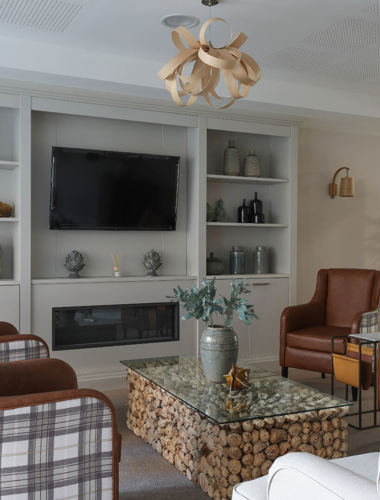 A living room in Spinnaker View, with multiple arm chairs around a coffee table and a wall-mounted TV next to them